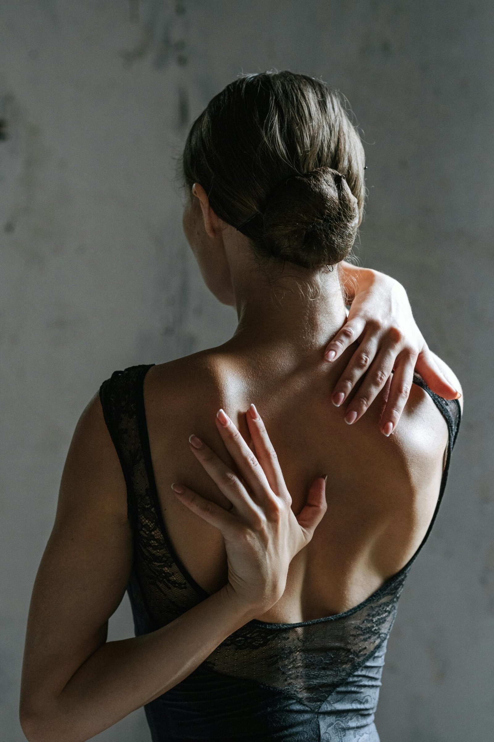 Back view of a woman stretching with hands behind her back in a black tank top